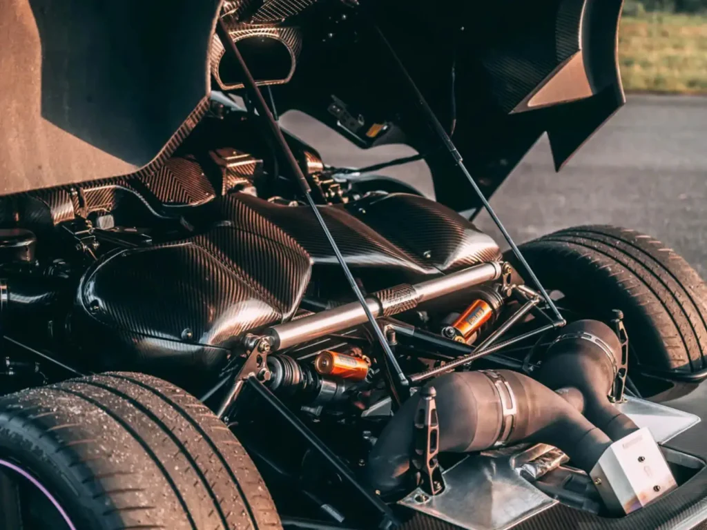 Exposed rear mechanical assembly of the Koenigsegg One:1 displaying suspension components, carbon-fiber structures, and high-performance engineering beneath the open rear clamshell