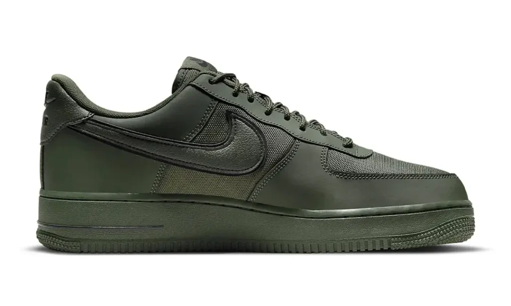 Medial side view of the olive Nike Air Force 1 Low. The sneaker features ballistic-style Cordura textile underlays, smooth synthetic mudguards, tonal stitching, a monochromatic midsole, and a large olive Swoosh extending across the side