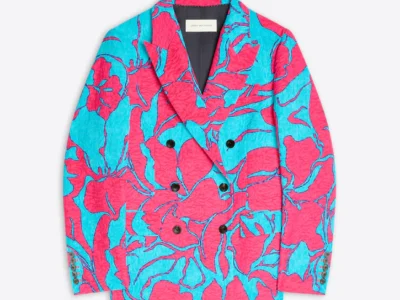 Bright double-breasted Dries Van Noten blazer featuring an oversized floral jacquard pattern in vivid pink and turquoise. The tailored silhouette is finished with dark buttons and a textured crinkled fabric that emphasizes the collection’s playful use of color and artistic expression
