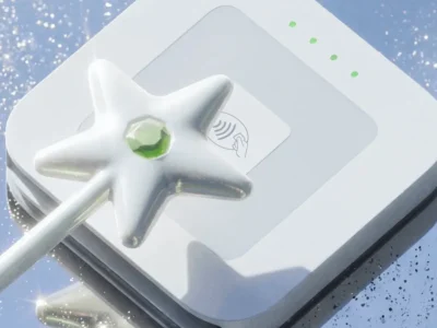 Cash App Wand contactless payment accessory featuring a pearlescent star-shaped design with a green gemstone center resting on an NFC payment terminal, highlighting the fintech brand’s playful approach to tap-to-pay tech