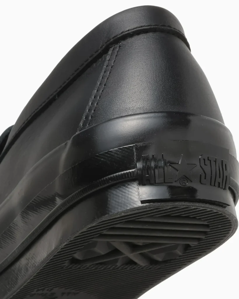 Close-up of the heel showing embossed All Star branding on the glossy black rubber heel counter, textured foxing, and outsole tread