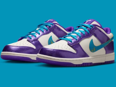 Nike Kobe x Dunk Low sneakers displayed in a three-quarter view against a bright turquoise backdrop. The pair features metallic purple reptile-textured overlays, crisp white leather panels, vibrant aqua-blue laces, and matching textured Swooshes with subtle yellow detailing. A white midsole and translucent purple outsole complete the bold, Lakers-inspired color palette