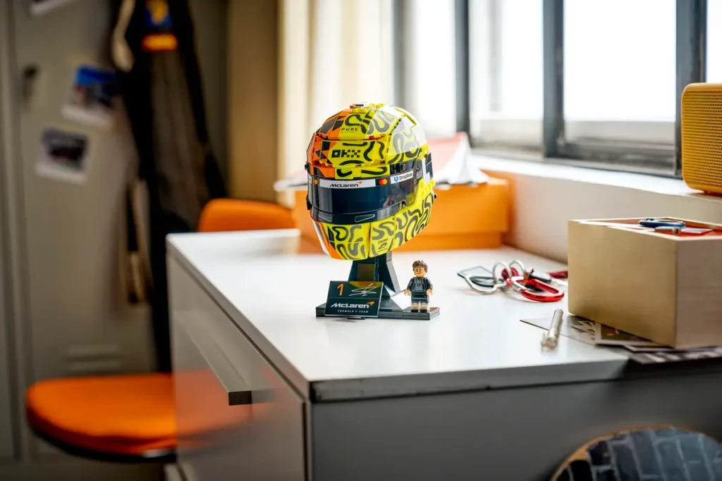 LEGO Lando Norris helmet model showcased on a desk near a window, emphasizing the collectible display format and authentic McLaren Formula 1 detail