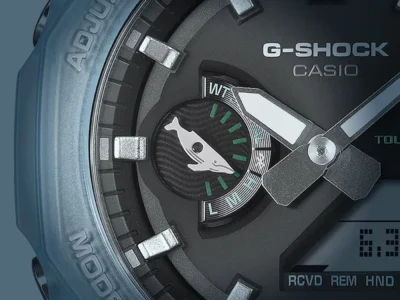 Macro close-up of the Casio G-Shock GA-B2100KB-2A dial, showcasing the translucent ocean-blue octagonal bezel, metallic hour markers, and distinctive whale-tail inspired subdial detail created for the ICERC Japan “Love The Sea and The Earth” collection