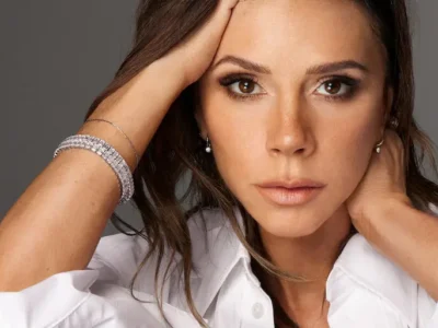 Victoria Beckham in a refined studio portrait wearing a crisp white shirt and diamond jewelry, exuding quiet confidence and modern elegance. Image from her Victoria Beckham brand campaign, featured alongside her first U.S. store opening in Miami’s Bal Harbour Shops