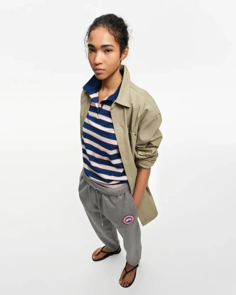 Model in a striped rugby-style polo, oversized utility overshirt, grey sweatpants, and sandals from the Canada Goose Summer 2026 Mainline Collection