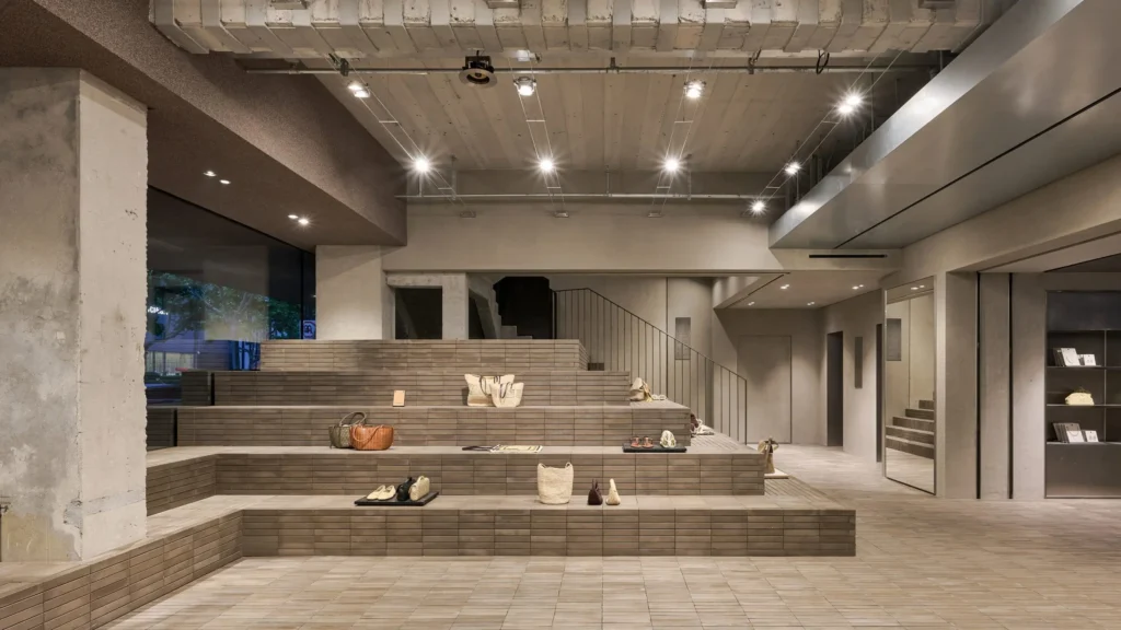 A refined womenswear display centered around a timber-framed merchandising fixture. Light pastel garments, dresses, and folded apparel are arranged against soft fabric backdrops, creating a calm and elegant shopping environment
