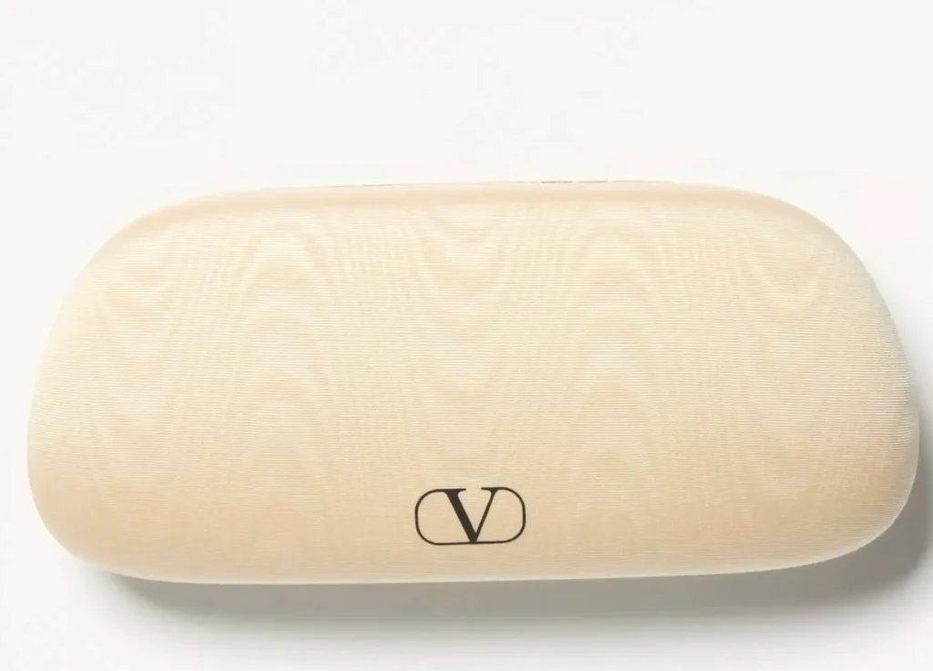 Cream-colored Valentino eyewear case with a soft textured finish and black VLogo Signature emblem, photographed against a clean white background in a minimalist product shot