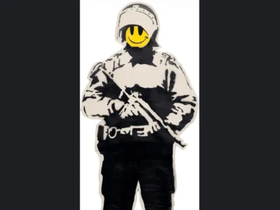 Full-screen view of the same stencil artwork displayed within a digital interface. The hooded figure, rendered in black-and-white spray-paint style, carries a rifle while a vivid yellow smiley face obscures the head. Dark side borders frame the artwork, emphasizing its presentation as a photographed or screen-captured street-art piece