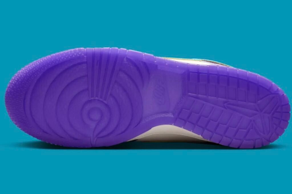 The underside of the Nike Kobe x Dunk Low is shown in full, highlighting a translucent purple rubber outsole with circular traction patterns, Kobe-inspired branding details, and segmented grip zones. The outsole sits against a vivid turquoise background that emphasizes the monochromatic purple finish