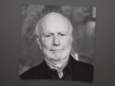 Black-and-white portrait of veteran television director and producer James Burrows. He faces the camera with a calm expression, wearing a dark jacket and collared shirt, set against a softly blurred background that emphasizes his distinguished career and show