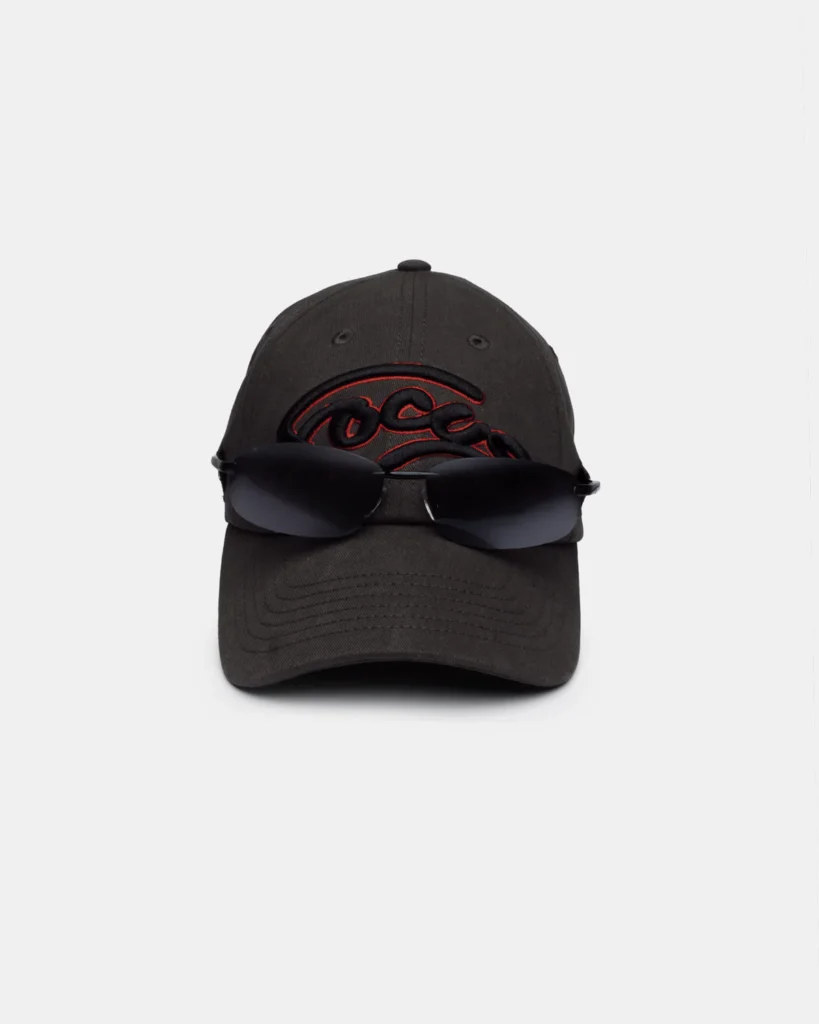 Dark charcoal baseball cap embroidered with a raised black-and-red script logo across the front. A pair of wraparound black sunglasses rests across the crown and brim, highlighting the cap's sporty style