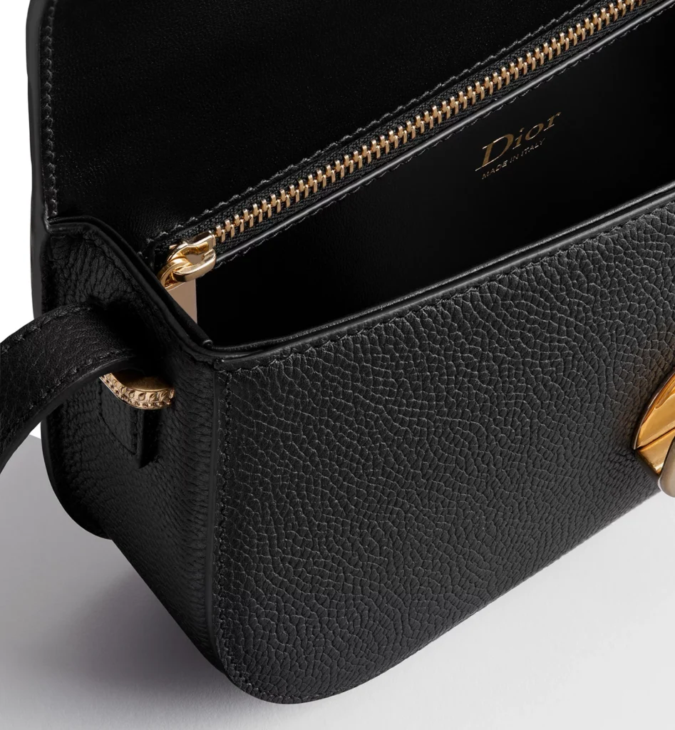 Close-up of the Small Dior Médaillon Flap Bag interior showcasing black leather lining, gold-tone zipper pocket, Dior Made in Italy signature, and finely textured grained calfskin construction