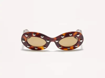 Valentino oval sunglasses in glossy tortoiseshell acetate featuring amber-tinted lenses and silver-tone stud embellishments surrounding each lens, shown from the front on a white backdrop