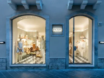Exterior view of a Prada boutique in Taormina, Italy, featuring elegant stone archways, illuminated display windows, and a refined luxury retail facade at dusk