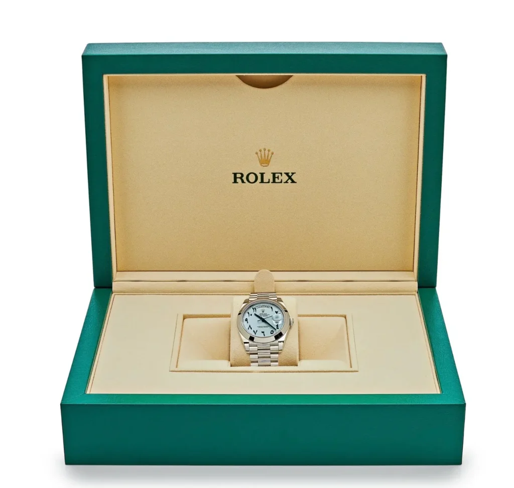 Rolex Day-Date presented inside an official green Rolex display box with cream interior, emphasizing the watch’s ice-blue Arabic dial and platinum construction