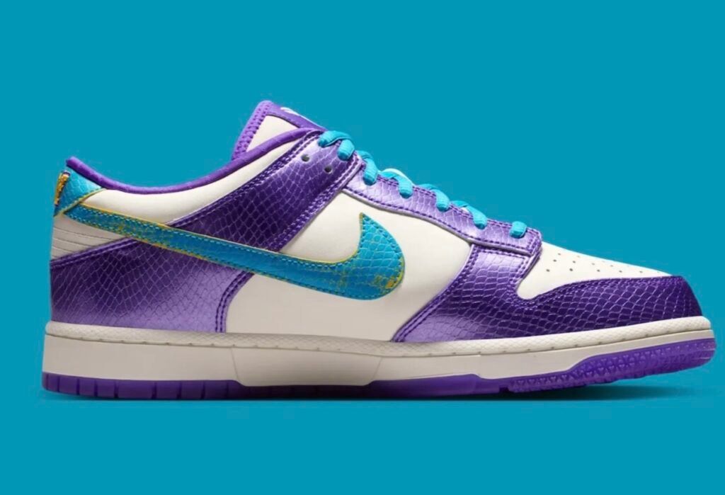 The medial side of the Nike Kobe x Dunk Low reveals the same metallic purple reptile-textured overlays and white leather construction. An oversized aqua-blue Swoosh wraps toward the heel, creating a dynamic visual effect, while the purple outsole and padded collar add depth and contrast
