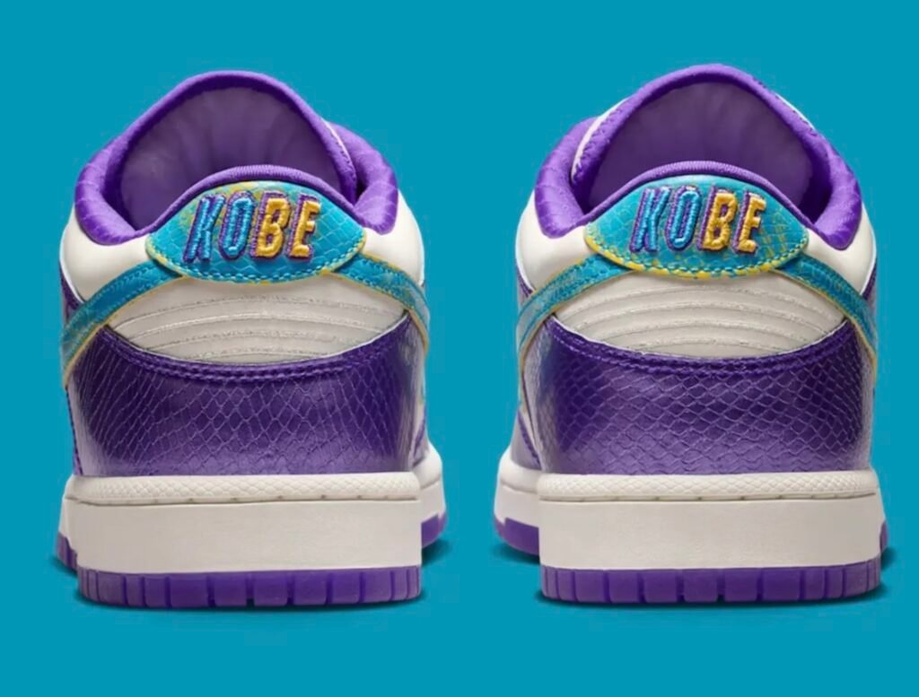 A rear-facing view highlights embroidered “KOBE” branding across both heel tabs in purple, aqua, and yellow thread. The metallic purple heel overlays, white leather heel panels, and aqua-blue heel wrap detail stand out against the vibrant turquoise backdrop, emphasizing the sneaker’s tribute-inspired design