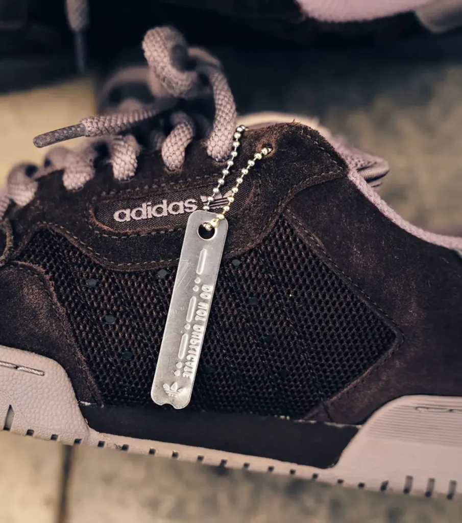 Close-up imagery reveals the collection metal hangtag attached to the eyestay, paired with textured suede and mesh panels that emphasize craftsmanship and durable