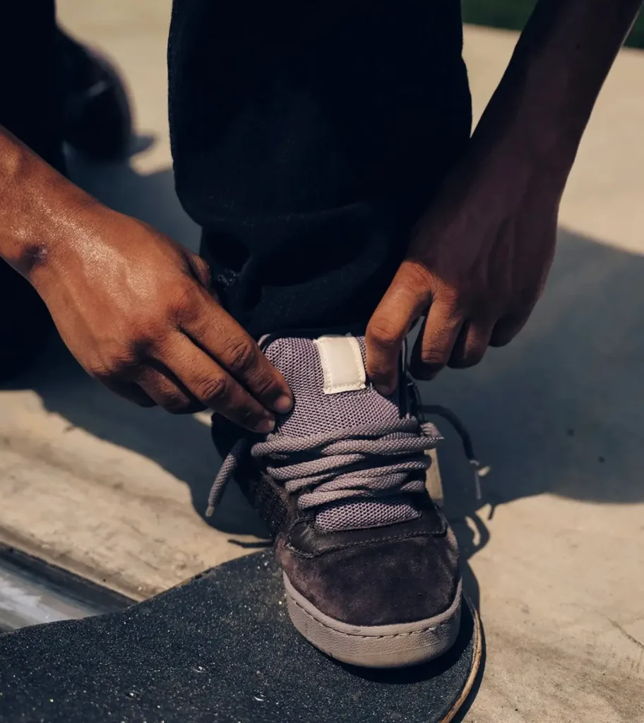 A skater adjusts the brown Powerphase before a session, drawing attention to the padded mesh tongue, oversized laces, and supportive low-cut design