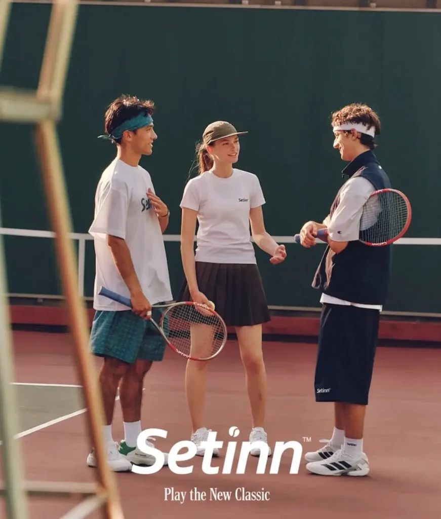 Three tennis players wearing Setinn apparel chat courtside while holding rackets, showcasing the brand’s modern sport-inspired show