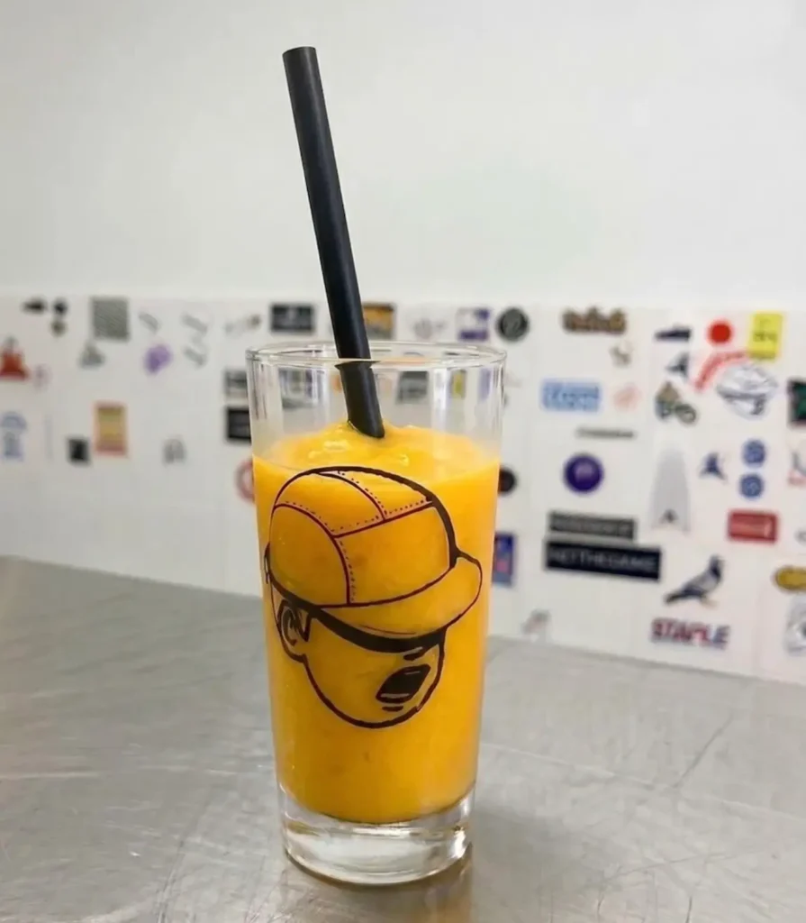 Bright orange smoothie served in a glass featuring Setinn’s signature mascot illustration, photographed inside the brand’s café-inspired space