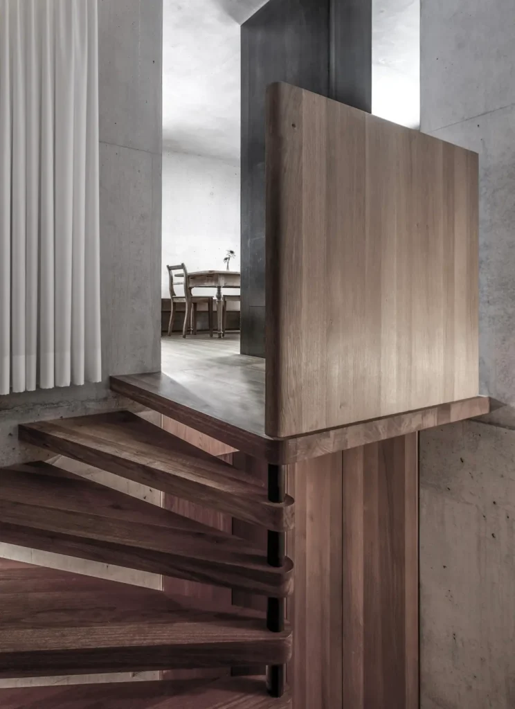 Contemporary alpine shelter blending textured concrete, exposed structural elements, and warm wood accents, designed to harmonize with its remote mountain set