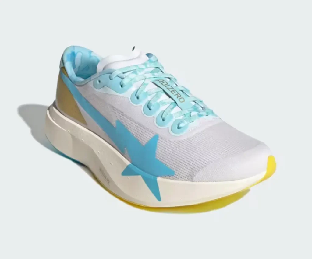 The lightweight runner is shown from a front angle, showcasing the oversized blue star graphic, streamlined white mesh construction, cushioned cream midsole, and bright yellow toe outsole accent