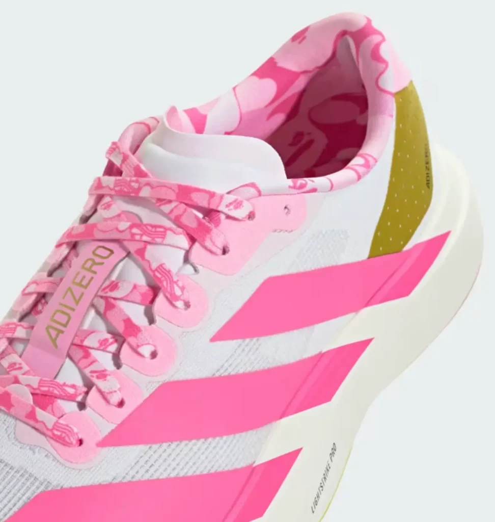A close-up of the pink edition highlights vibrant pink Three Stripes, matching BAPE camouflage laces and lining, metallic gold heel detail, breathable white mesh, and the Adizero lace tab