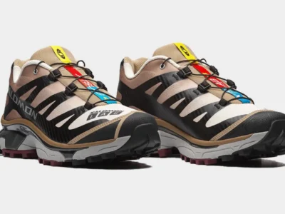 Three-quarter front view of a pair of Salomon XT-LAB trail running shoes displayed together. The design combines cream mesh, black structural overlays, tan panels, colorful XT-LAB tongue branding in blue, red, and yellow, Quicklace fastening, and a chunky performance trail sole with deep burgundy tread