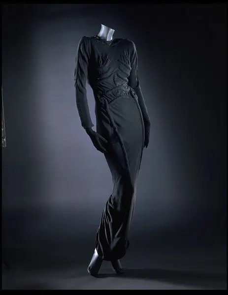 Iconic black evening gown displayed on a mannequin, featuring padded skeletal rib and spine elements that transform the garment into a wear surrealist sculpture