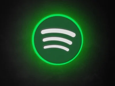 Spotify logo displayed as a glowing neon-style sign against a dark black background. The iconic green circular emblem emits a bright luminous halo, highlighting the white curved sound-wave bars at its center. The minimalist composition creates a futuristic, atmospheric look that emphasizes Spotify's recognizable brand identity through vibrant green illumination and subtle light gradient