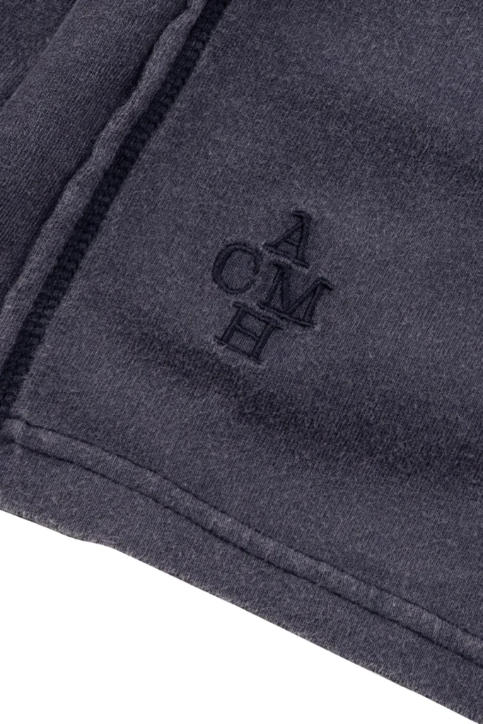 Close-up of the sweatshirt’s washed charcoal fabric featuring a subtle embroidered logo near the hem