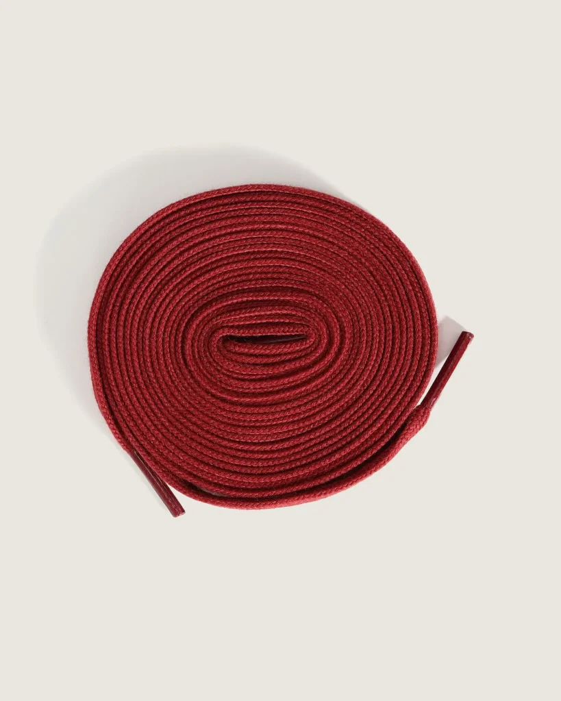 Extra pair of dark red flat laces included with the Vans Skate Old Skool 36+ Evisen Skateboards collision, coiled against a neutral backdrop
