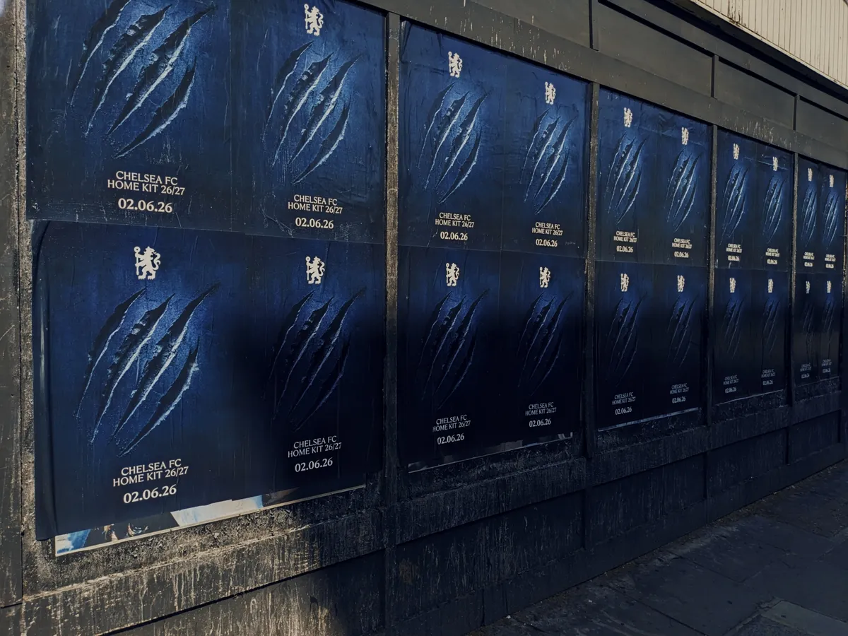 A row of Chelsea FC 2026/27 home kit teaser posters displayed along a city wall, featuring dark blue backgrounds, claw-mark graphics, lion emblems, and the launch date as part of the club’s “Can’t Tame Us” campaign