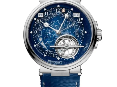 Breguet wristwatch with a blue celestial dial featuring constellation artwork, calendar displays, exposed tourbillon, polished case, and textured blue strap