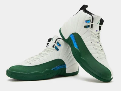 Pair of Air Jordan 12 shoe displayed against a light gray background, featuring white tumbled leather uppers with deep emerald-green mudguards and midsoles. Iridescent blue metallic eyelets and matching side accents add contrast, while black tongue liners and subtle purple detailing complete the classic basketball silhouette