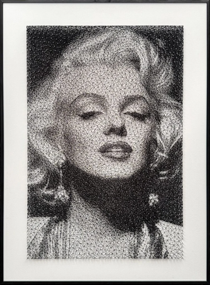 Framed monochrome artwork depicting Marilyn Monroe created from an intricate web of intersecting black lines, forming a detailed portrait with closed eyes, softly styled hair, and iconic Hollywood glamour