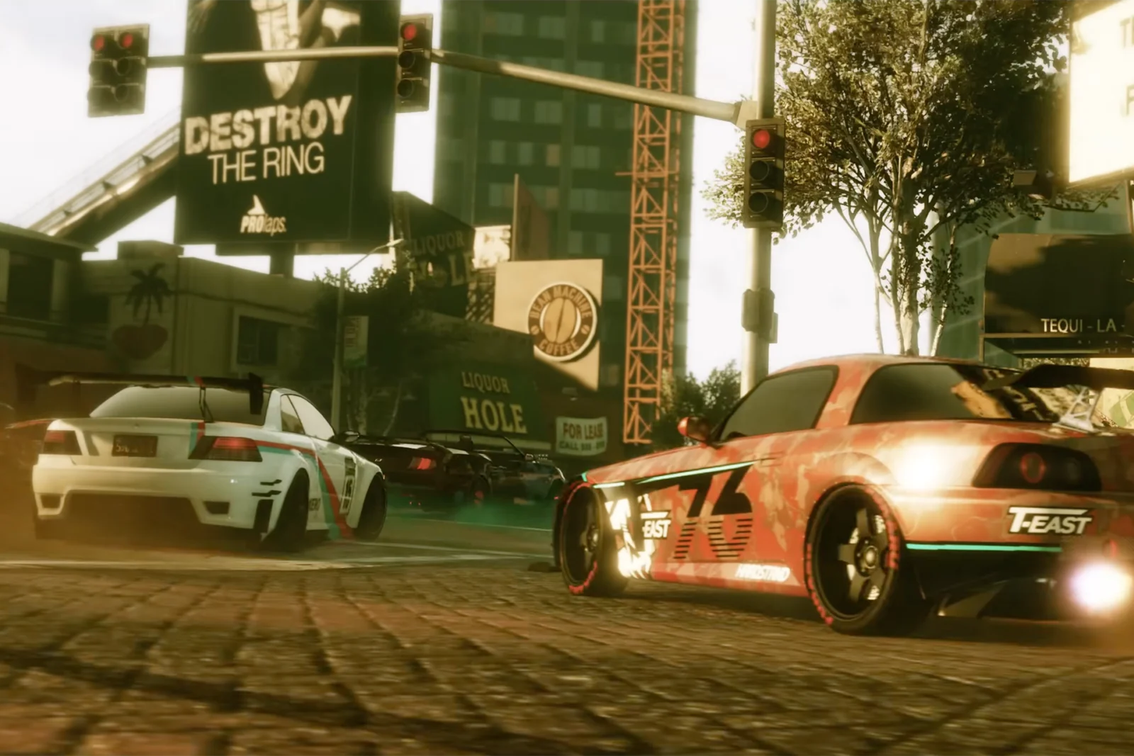 Street racing scene set in a sunlit urban intersection, featuring customized tuner cars drifting through city streets. A red-and-black widebody coupe dominates the foreground with racing graphics, oversized wheels, and a large rear wing, while a white race-inspired sedan slides through the turn ahead. Towering billboards, traffic lights, and downtown buildings frame the action, creating a cinematic atmosphere filled with speed, tire smoke, and high-energy motorsport culture