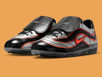 Angled product shot of the Patta x Nike Cryoshot Mercurial R9 against a warm orange backdrop, emphasizing its football-inspired silhouette, glossy finishes, and translucent cushioning platform
