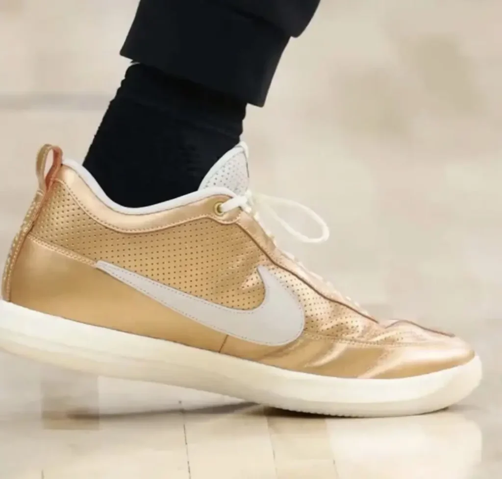 Detailed on-foot view of the metallic gold Nike BOOK 2 PE worn by Devin Vassell, showcasing reflective gold finishes, white laces, perforated panels, and championship-inspired style