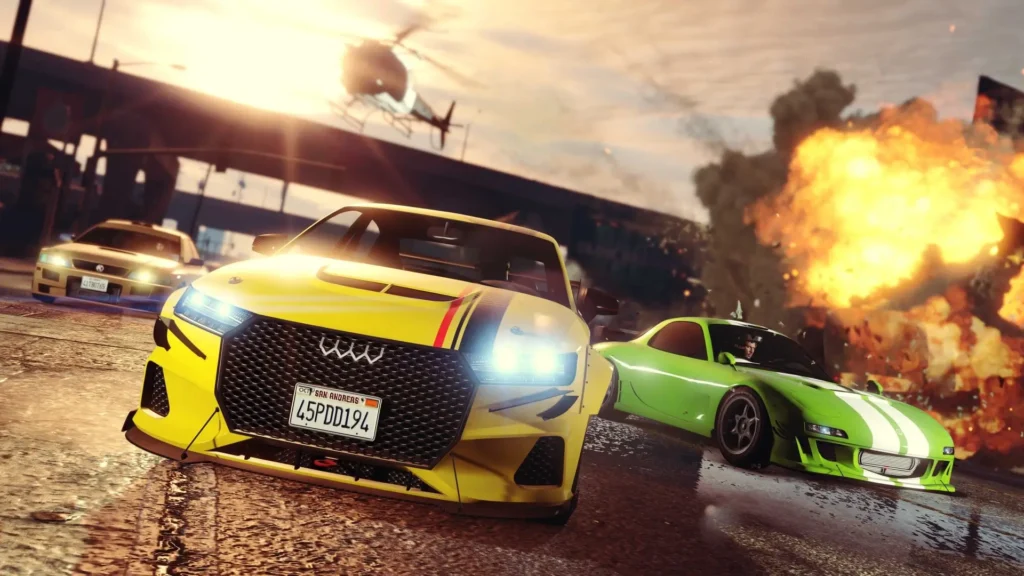 Action-packed racing scene featuring customized sports cars speeding through a city street as a massive explosion erupts in the background. A bright yellow performance sedan dominates the foreground with illuminated headlights and aggressive bodywork, while a green tuner car and a police vehicle follow behind. A helicopter hovers overhead against a dramatic sunset sky, creating a cinematic atmosphere filled with speed, chaos, and high-stakes pursuit