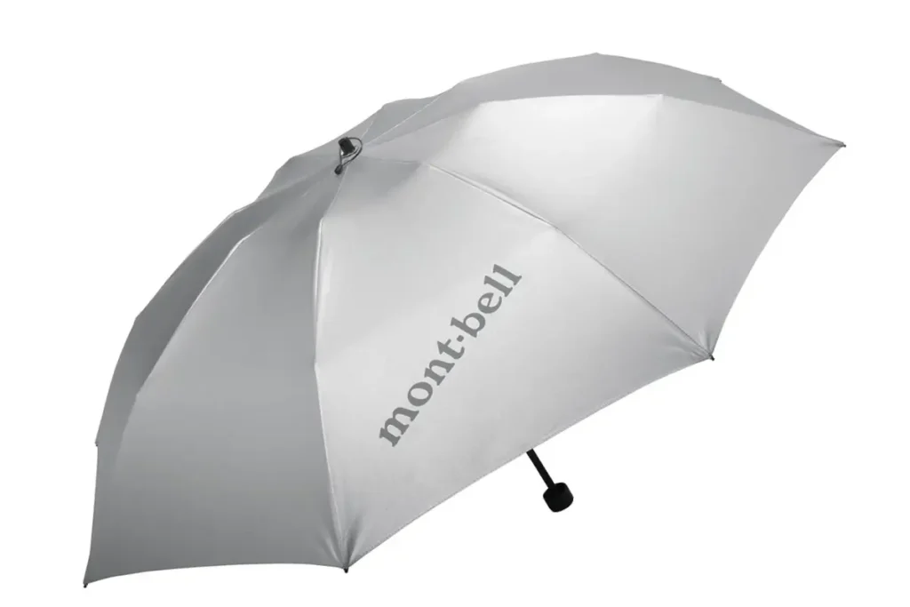 Light silver-gray Montbell travel umbrella with a clean, understated appearance and tonal logo branding. Open canopy displayed against a neutral background
