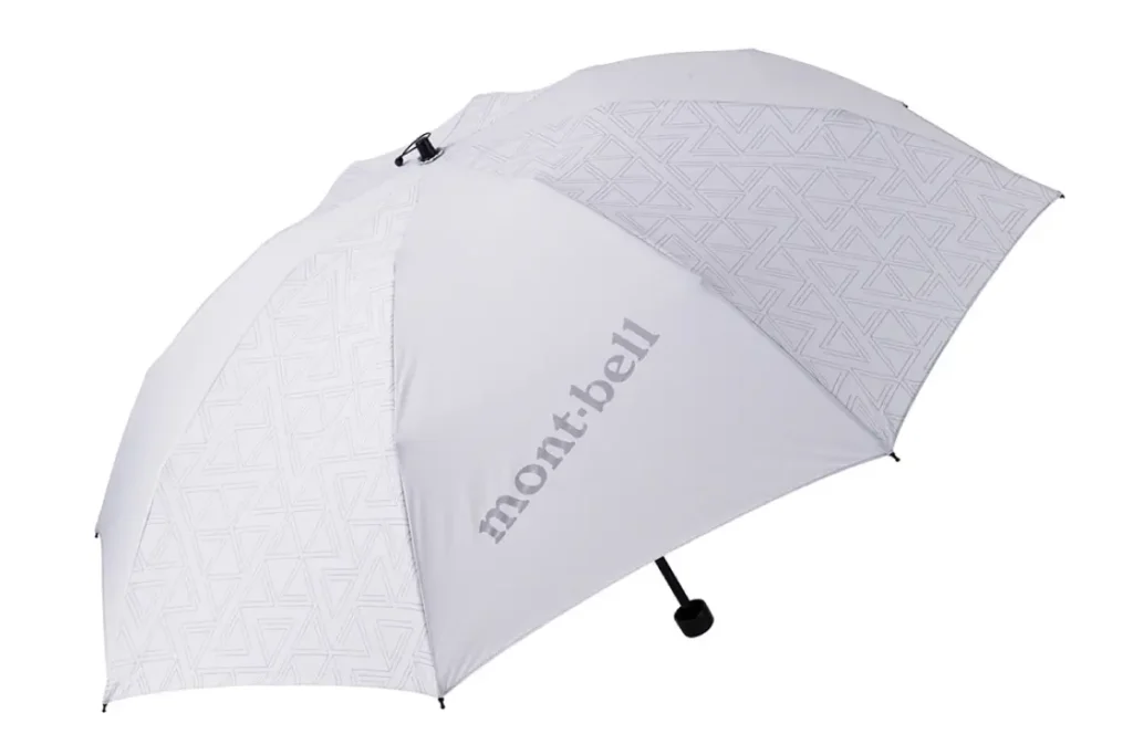 White Montbell folding umbrella with subtle tonal geometric triangle graphics across select canopy panels and silver-gray logo branding, combining view with min style