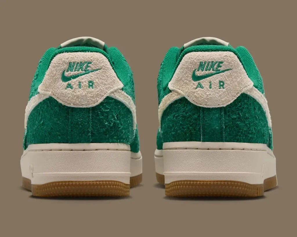Rear view of the pair showcases cream suede heel tabs embroidered with green Nike Air branding. The shaggy green overlays extend around the heel, while the gum outsole peeks out beneath the off-white mid