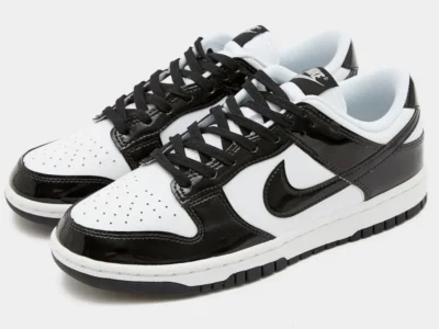 Pair of Nike Dunk Low "Panda Patent" shoe in three-quarter view showcasing shiny black patent leather overlays, white leather uppers, black laces, and a timeless monochrome design