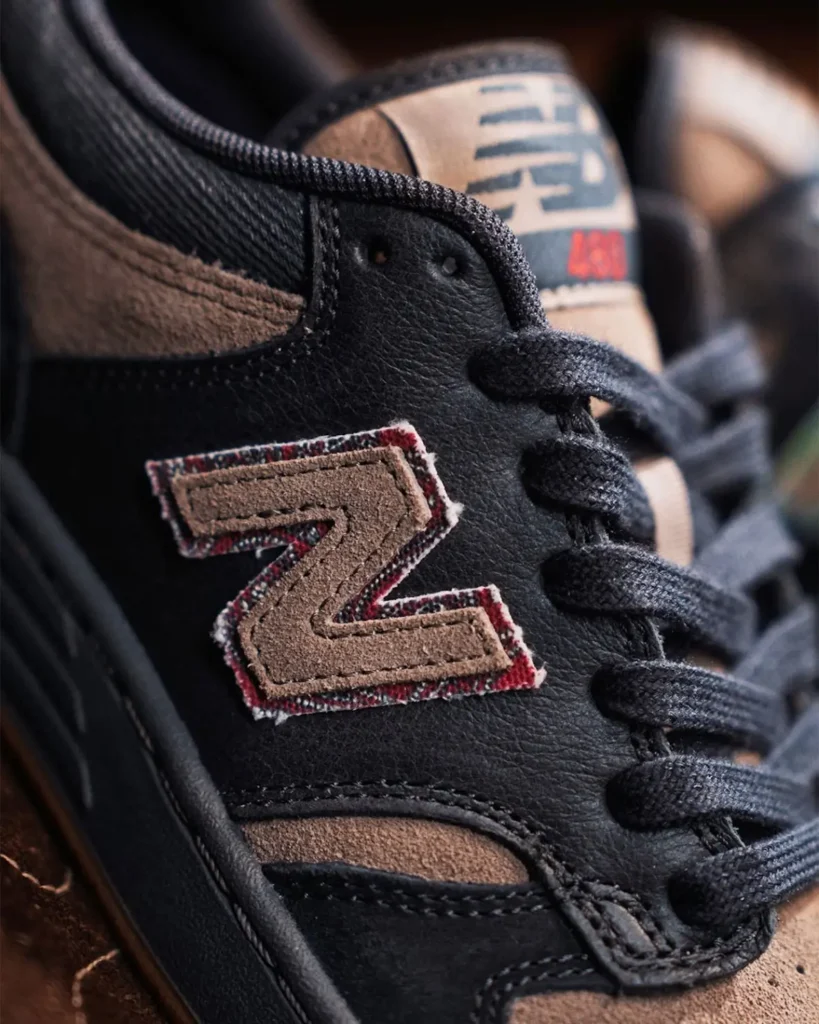 Macro photograph of the lateral side of the New Balance Numeric 480 highlights the textured suede-and-leather construction, black laces, and a vintage-inspired chenille-style “N” logo patch