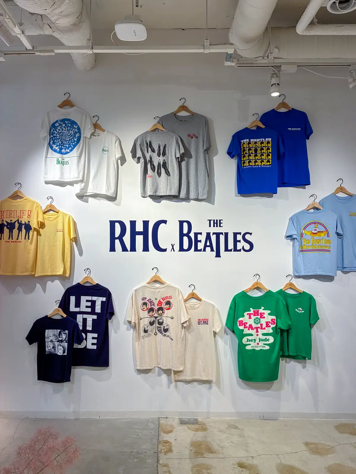 Wall display of Ron Herman California x The Beatles graphic T-shirt collection featuring vintage-inspired designs, album artwork references, and colorful music-themed print