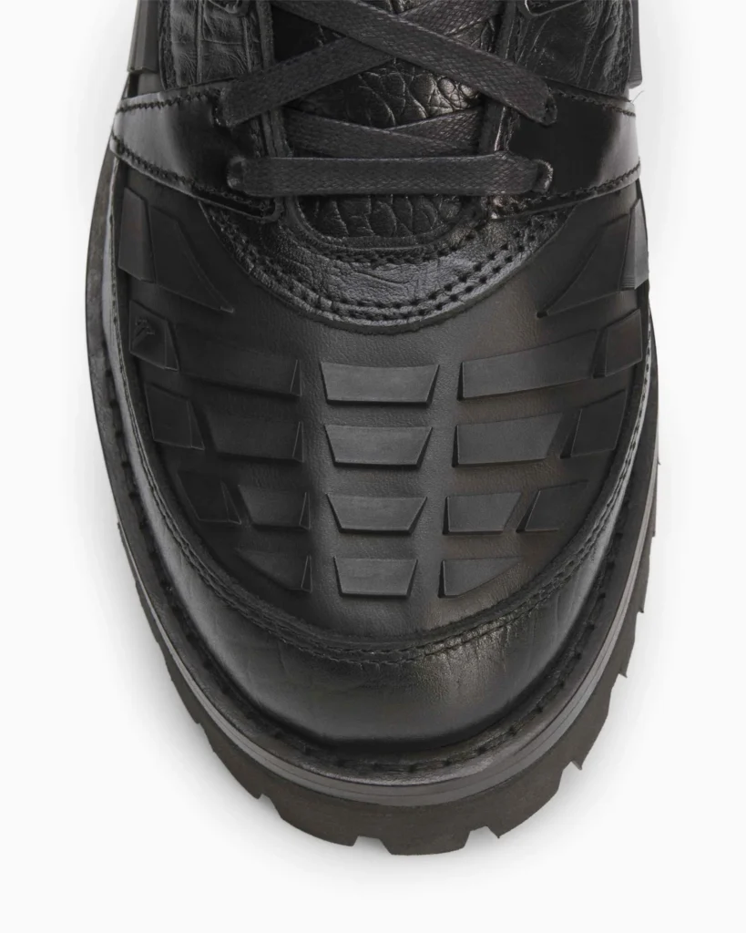 Close-up of the forefoot area revealing the matte black Predator strike elements layered over premium leather, contrasted by detailed stitching and tonal lacing