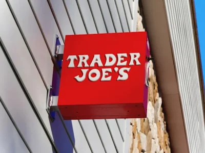The red exterior sign of a Trader Joe's grocery store, photographed from below against a bright blue sky